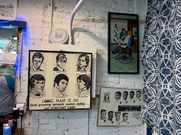 Vintage 'Long Hair Is In!' poster and barbering artwork on the shop wall